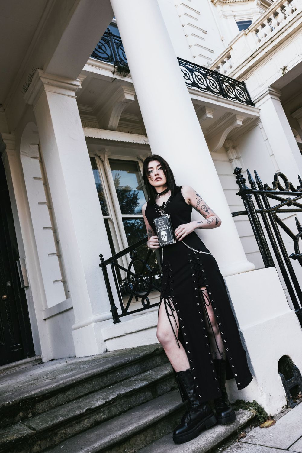 Gothic styled alternative model with dark hair posing outside a white & black building in Hove for a small fashion brand