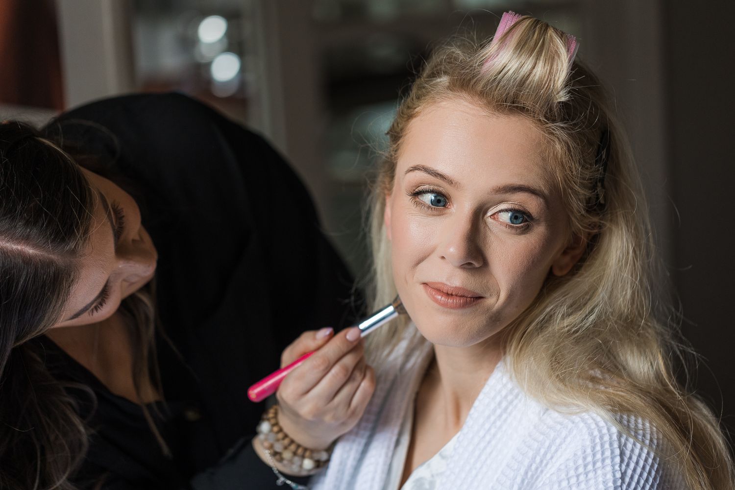 Professional makeup artist applying cosmetics during bridal preparation.