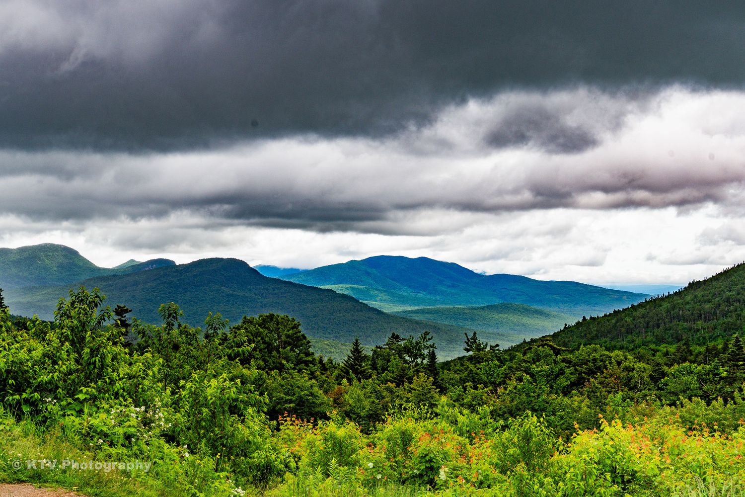 Panoramic view of green mountains under dramatic storm clouds in New England.