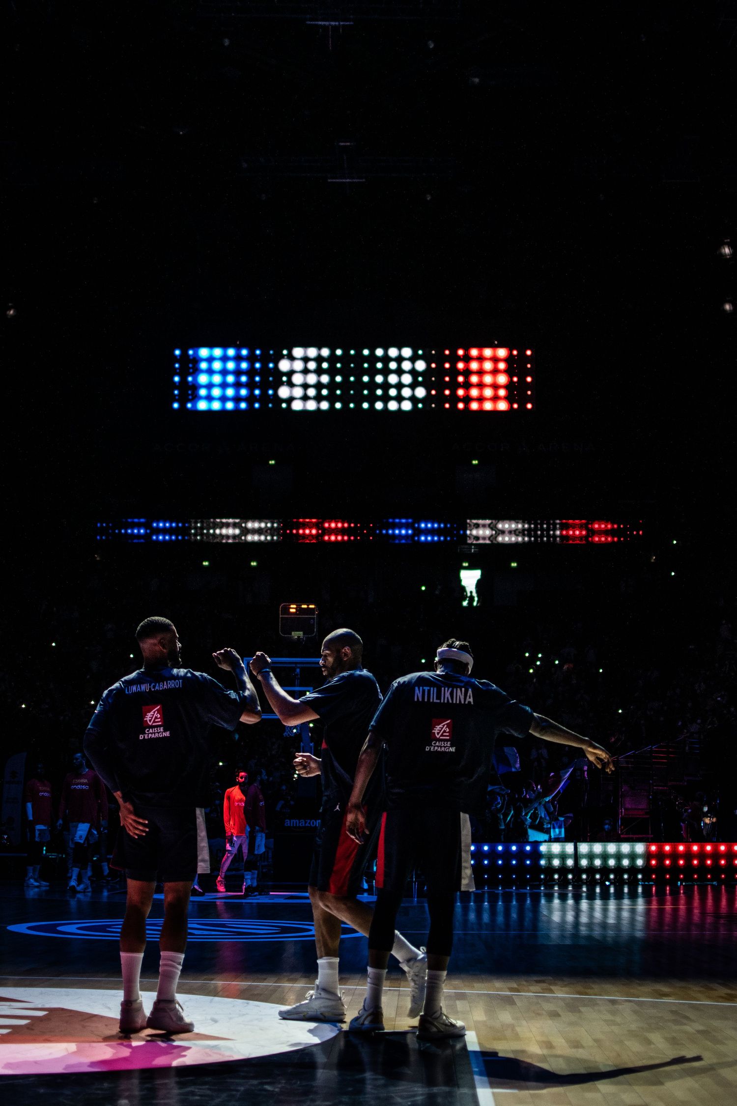 Basketball players huddled together under arena lights during game.