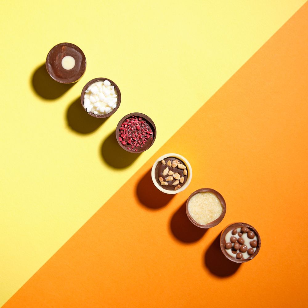 Bold, eye-catching image of delicious miniature chocolate cups on a bright yellow and orrange background.