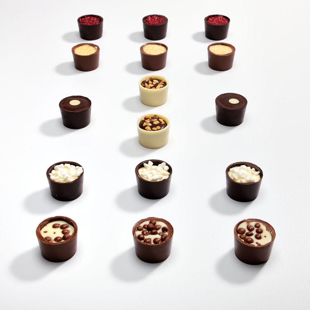 Milk, white and plain chocolate cups on a simple white background.