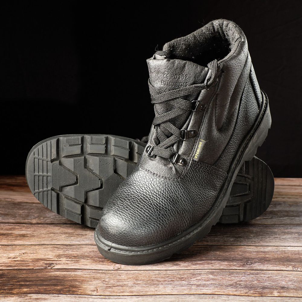 e-Commerce shot of safety boots on a rough wooden floor against a black background.