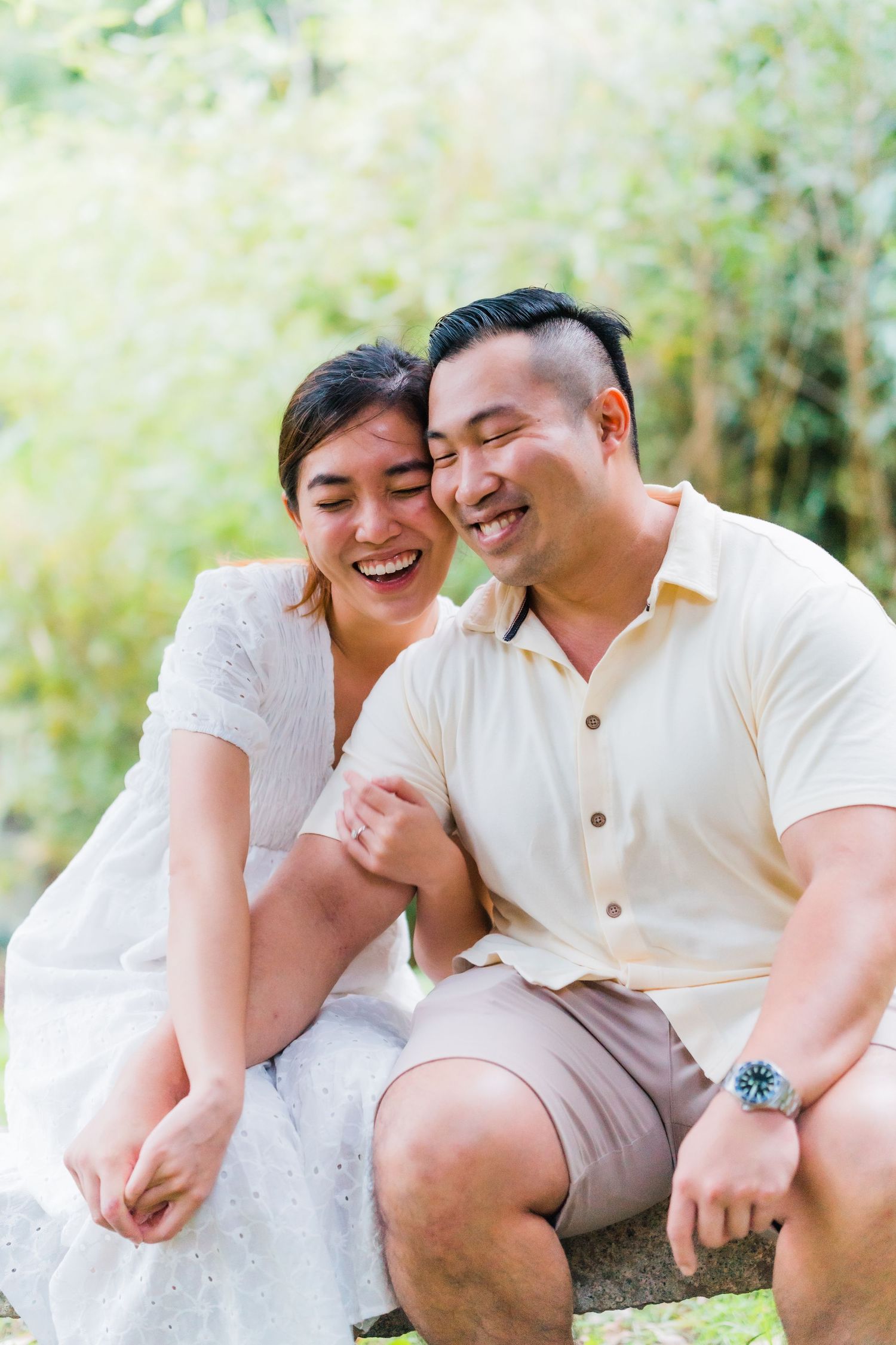 A couple shares a candid laughing moment together outdoors in natural lighting.