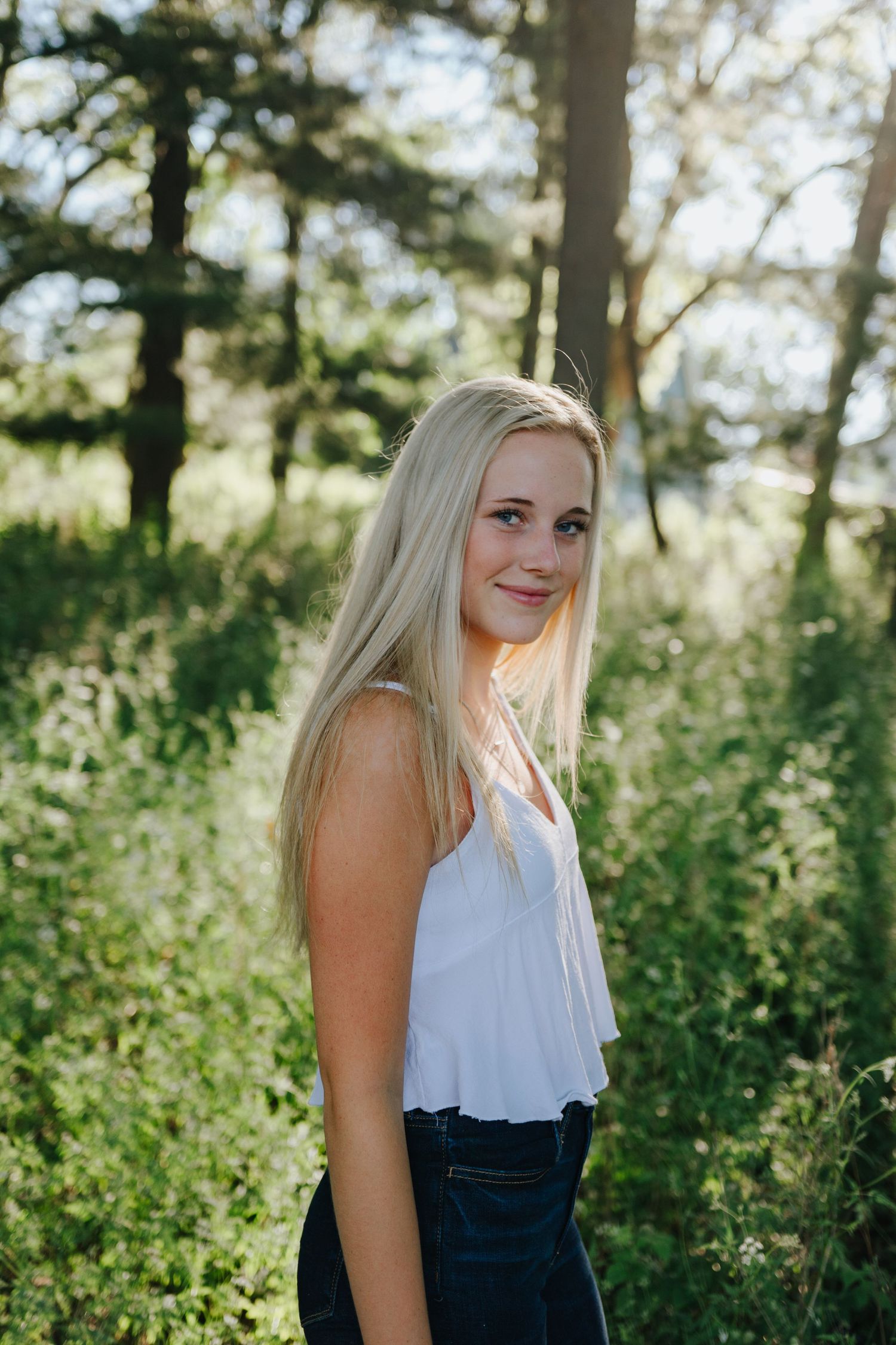 Portrait series in white top against natural forest background.