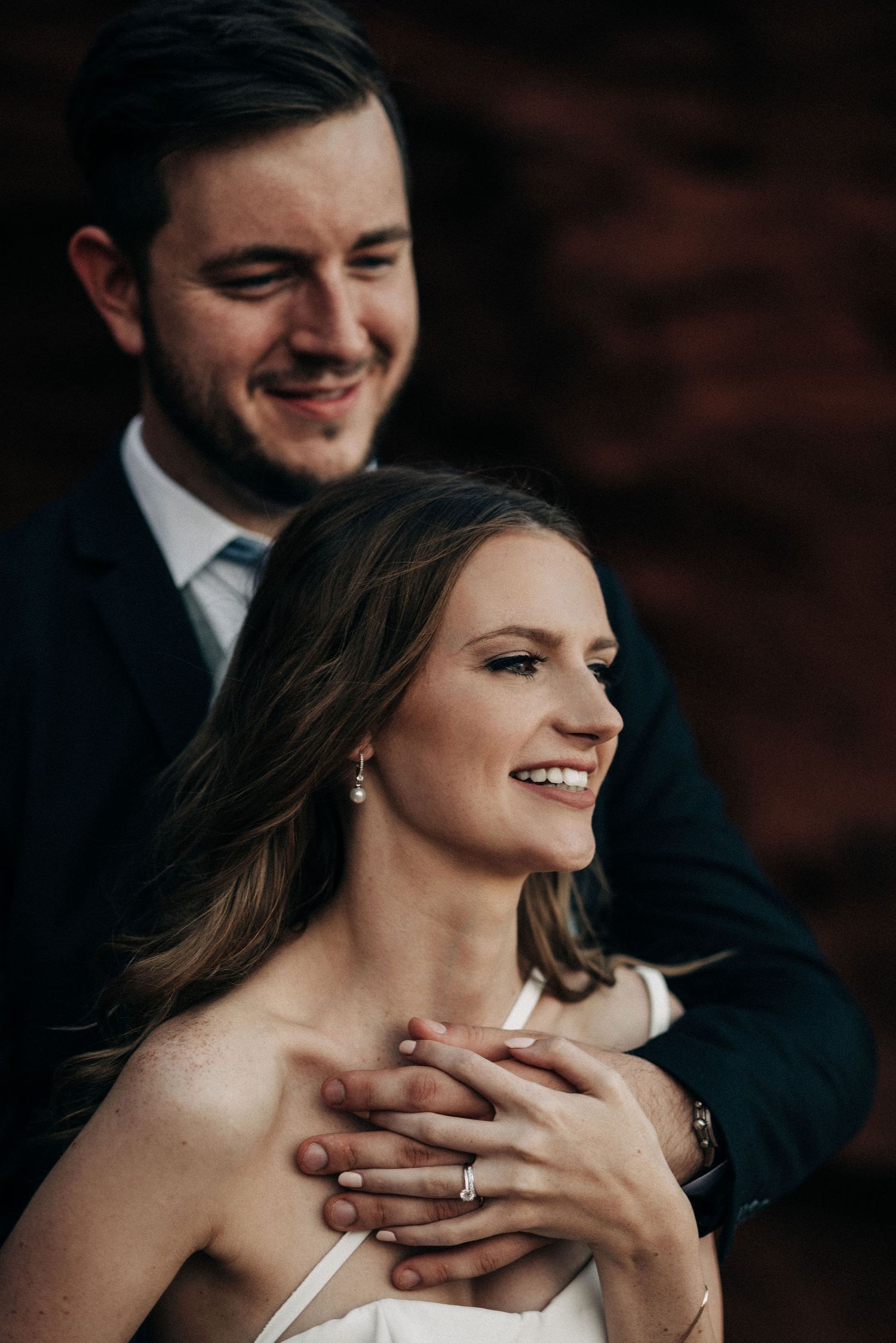 Romantic wedding portrait showcasing an intimate embrace against a dark background.