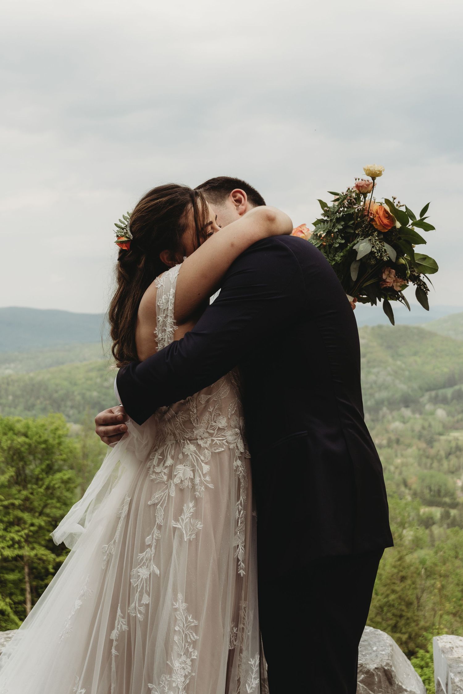Romantic embrace of newlyweds with mountain vista backdrop.