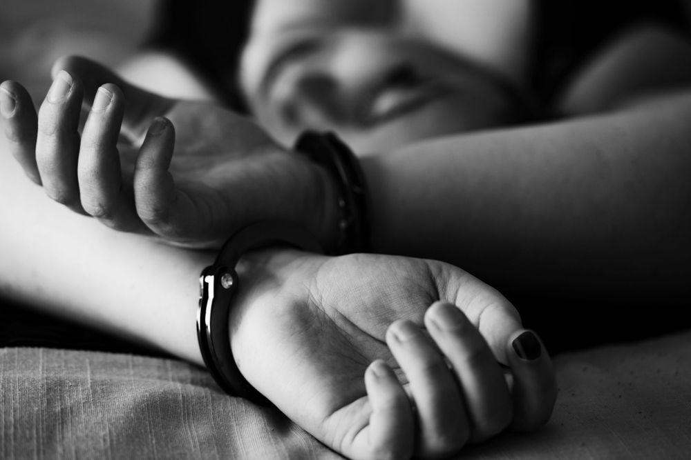 woman laying on back with hands crossed above head wearing handcuffs