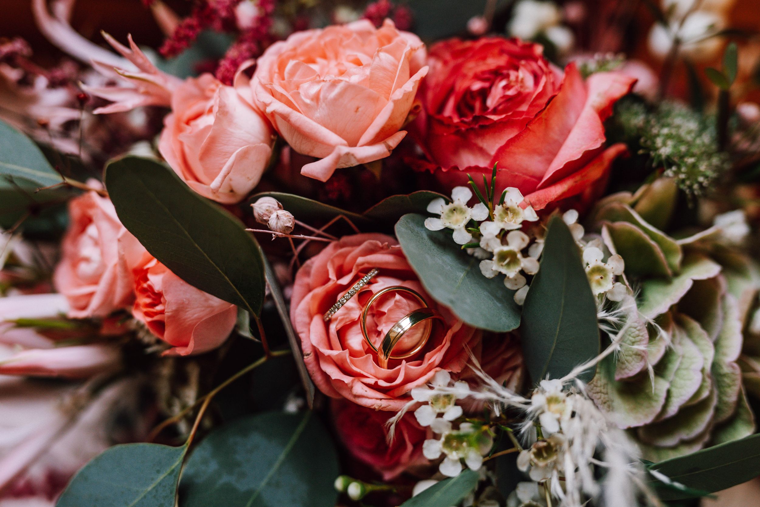 Beautiful wedding bouquet with pink and red roses mixed with delicate white flowers and greenery.
