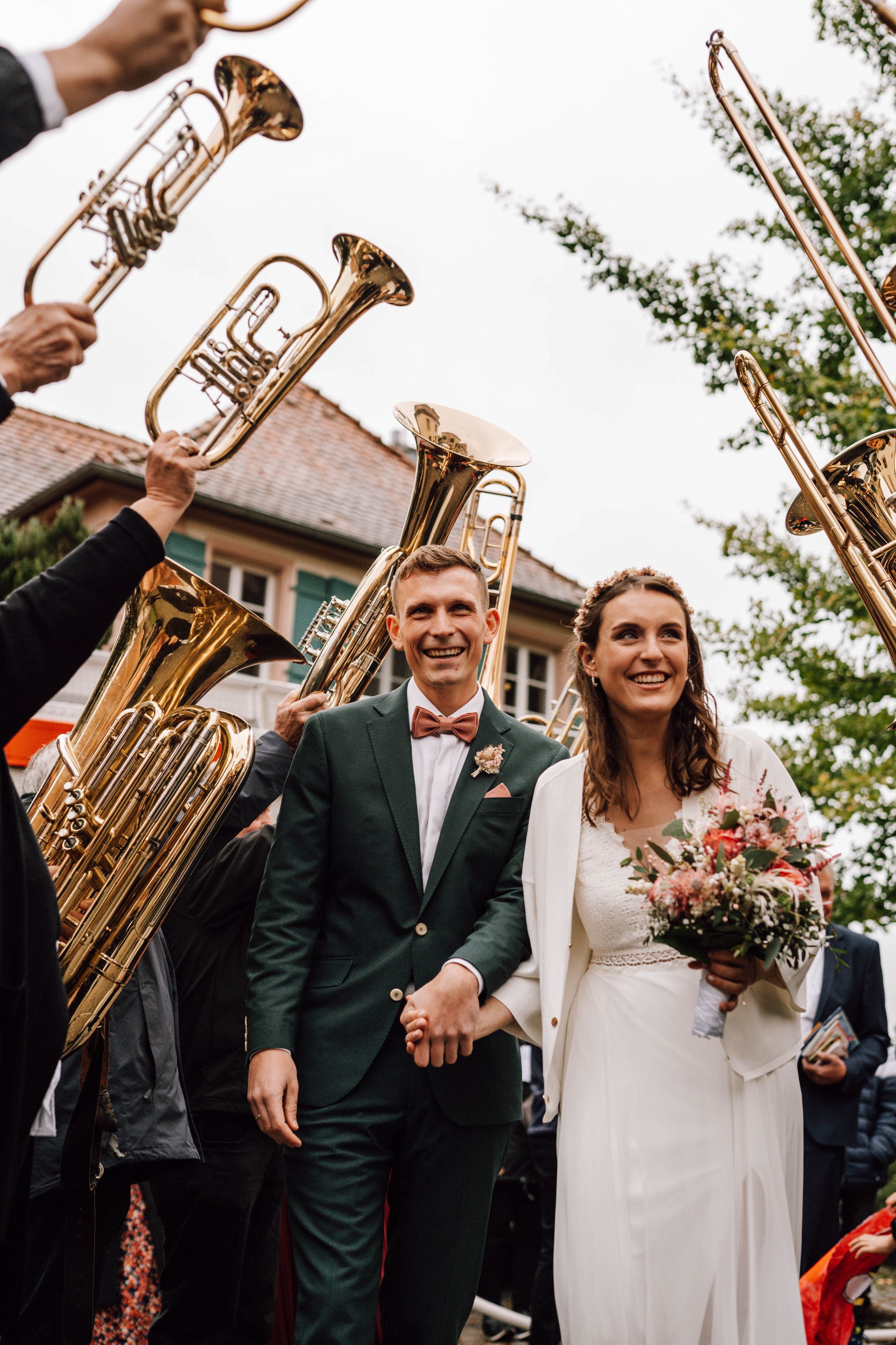 Wedding celebration with brass instruments and floral bouquet outdoors.