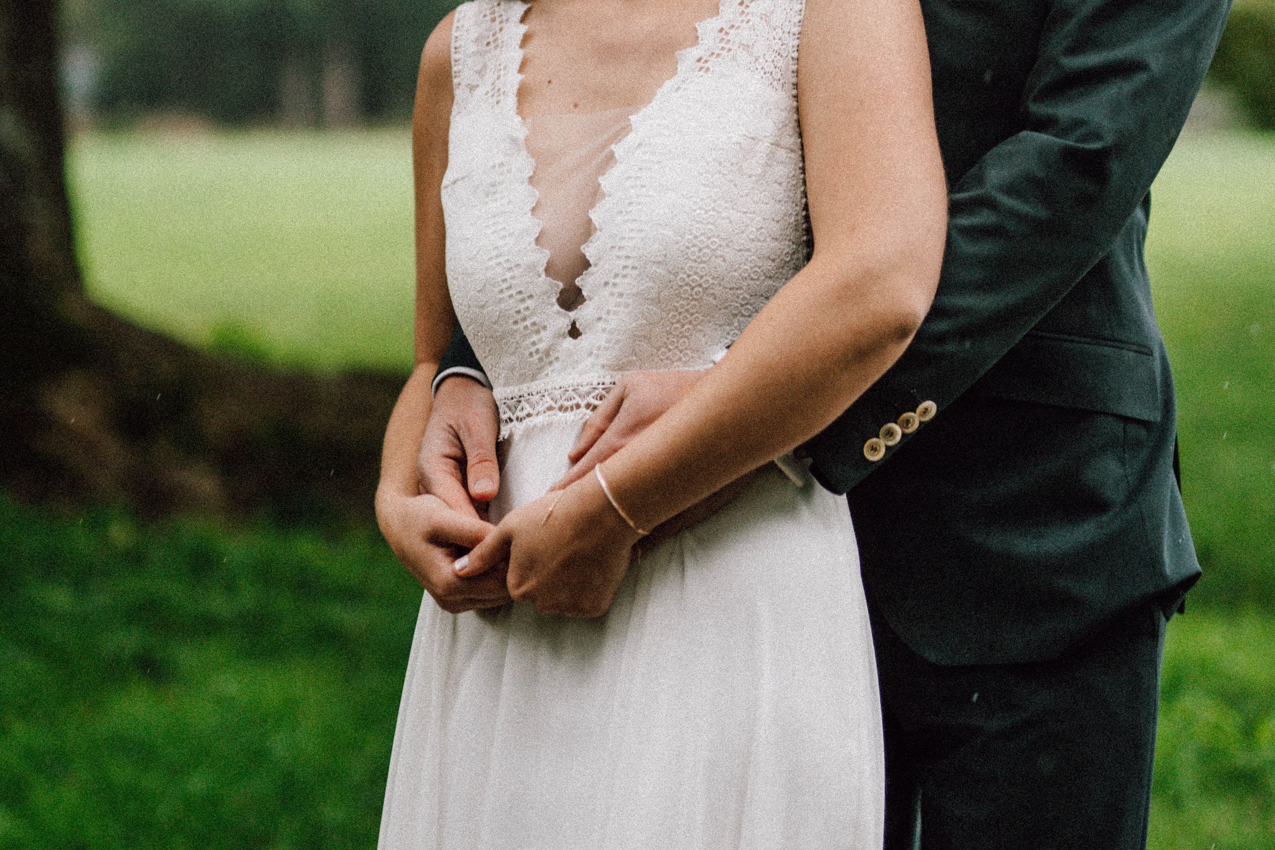 Intimate detail shot of couple's embrace in elegant wedding attire.