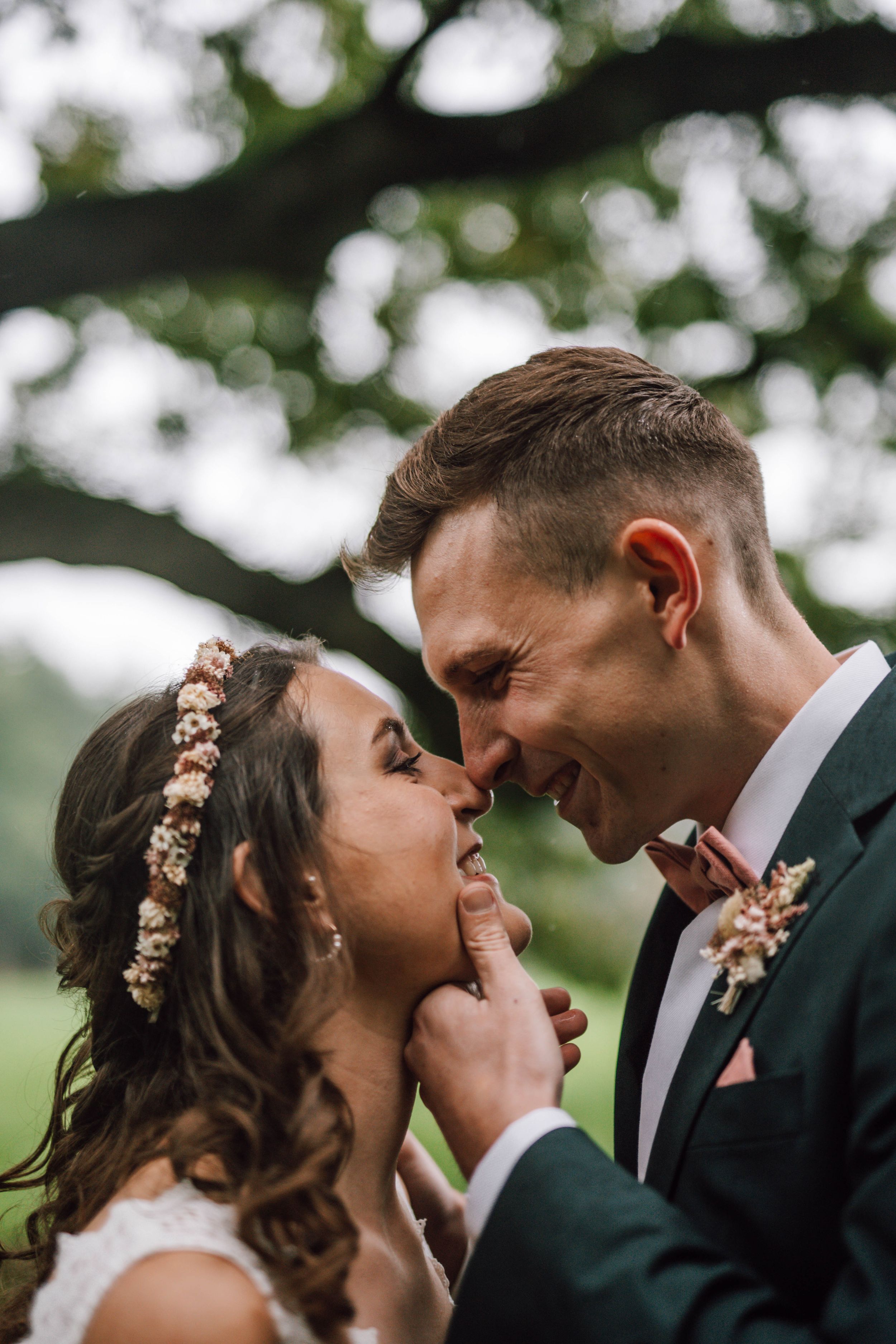 Intimate moment between newlyweds sharing laughter in an outdoor garden setting.