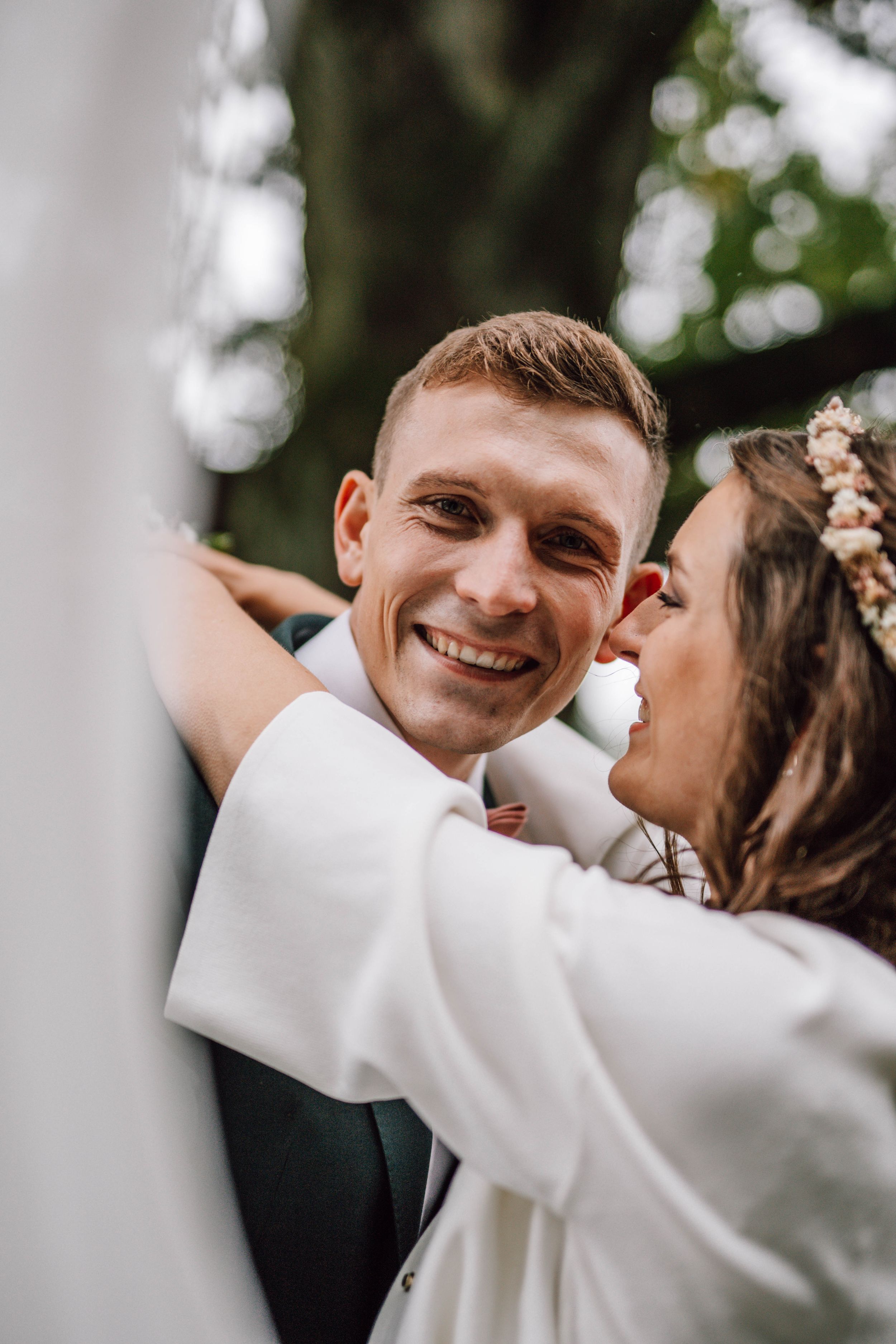 A joyful wedding moment captured between newlyweds sharing an intimate embrace outdoors.