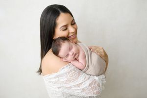Mother and baby sharing tender moment against white background.