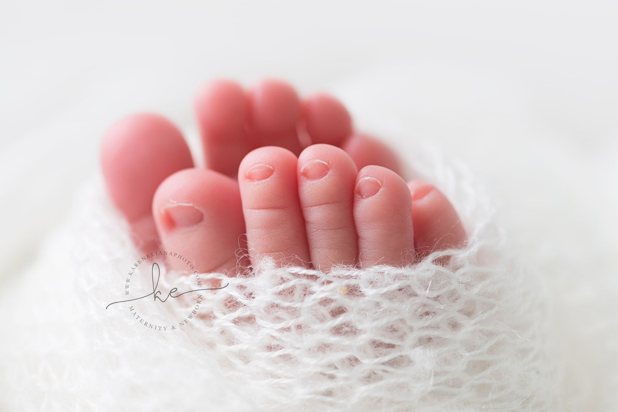 Close-up of tiny baby toes resting on white lace fabric.