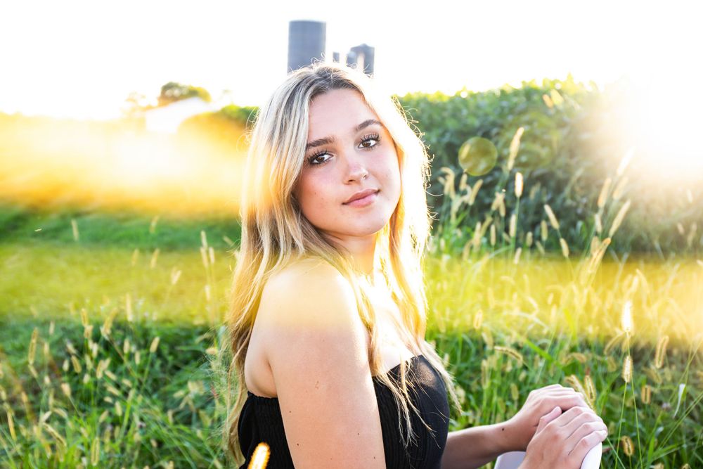 Sunset portrait with backlit golden glow against a natural farm landscape.