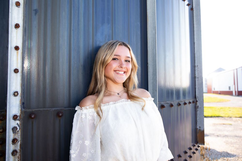 Outdoor fashion photo with white peasant top against industrial metal background.