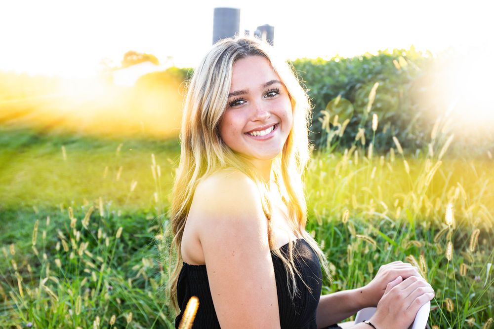 Joyful summer portrait outdoors with warm sunlight and agricultural setting.