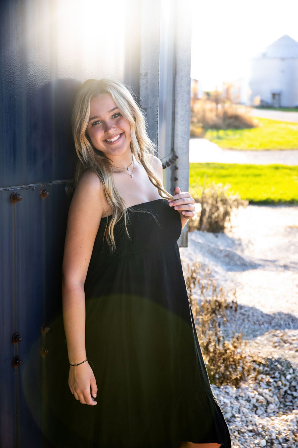 Summer fashion portrait in black sundress with industrial and rural background.