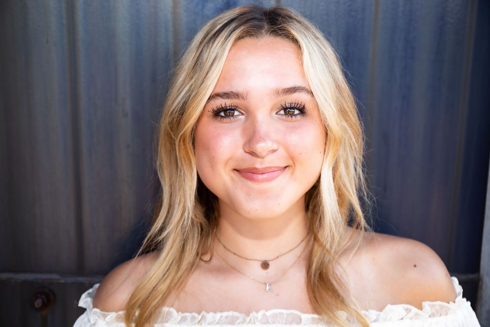 Close-up portrait showcasing natural makeup and a white off-shoulder blouse.