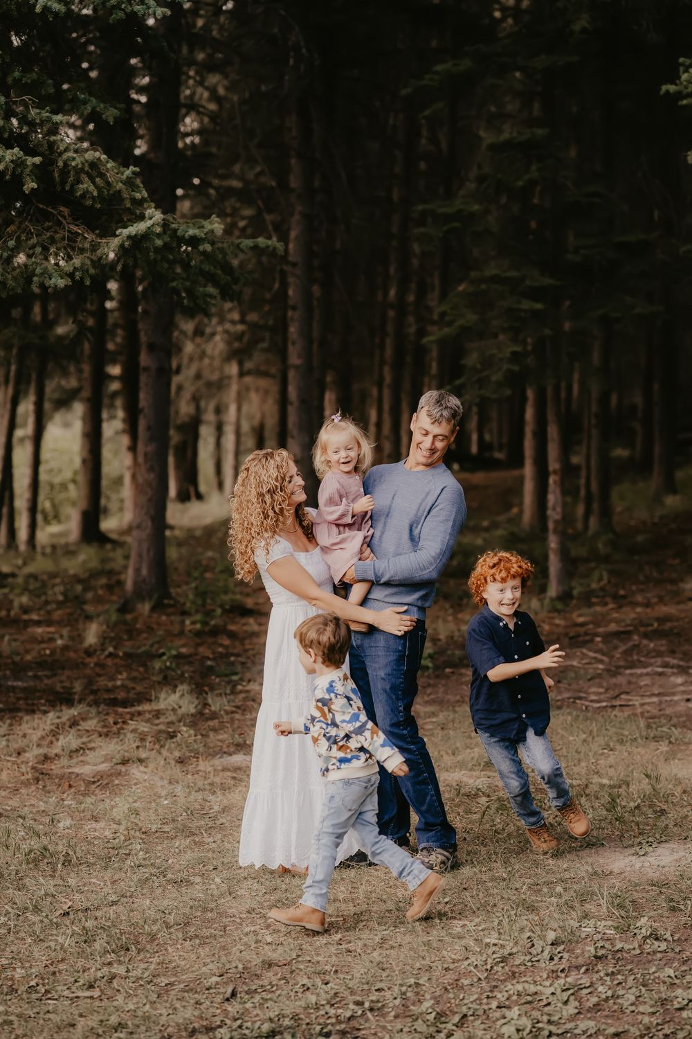 Playful family moment captured in a wooded forest setting.