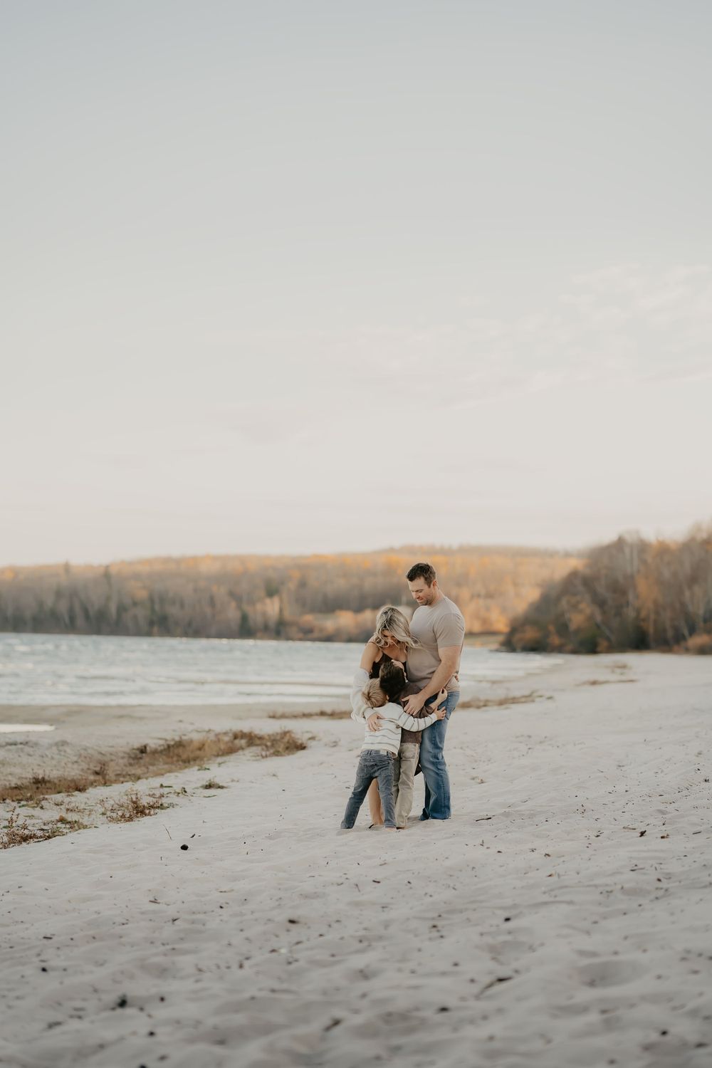 Family sharing intimate moments on a sandy beach at sunset.