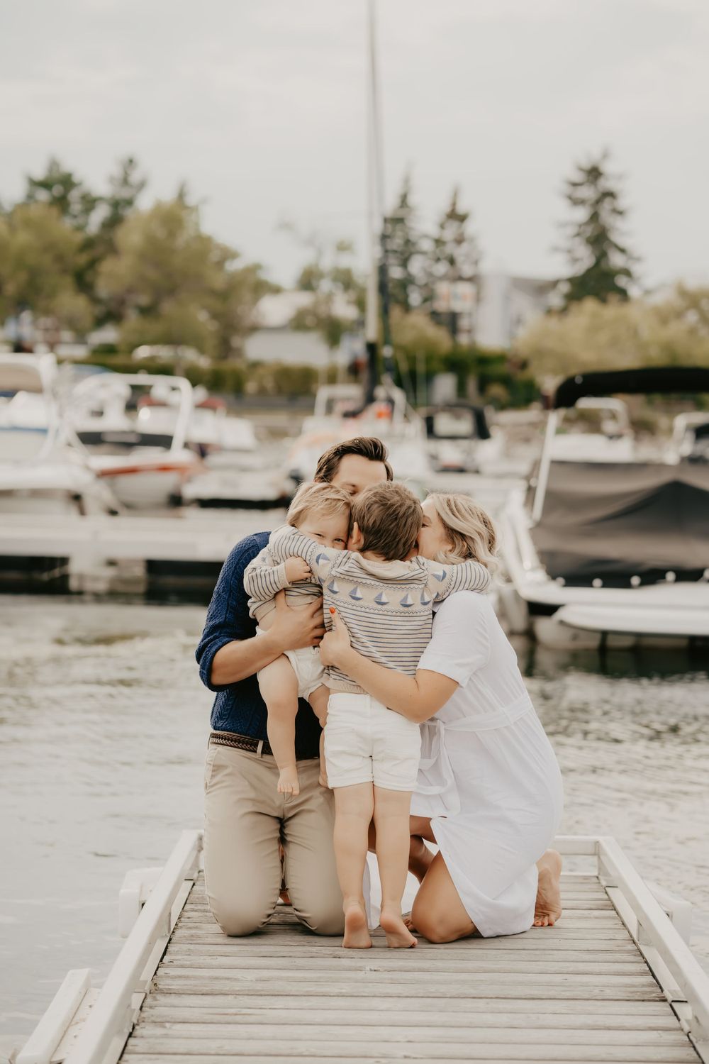 Group sharing intimate moments on a wooden pier with boats in the background.