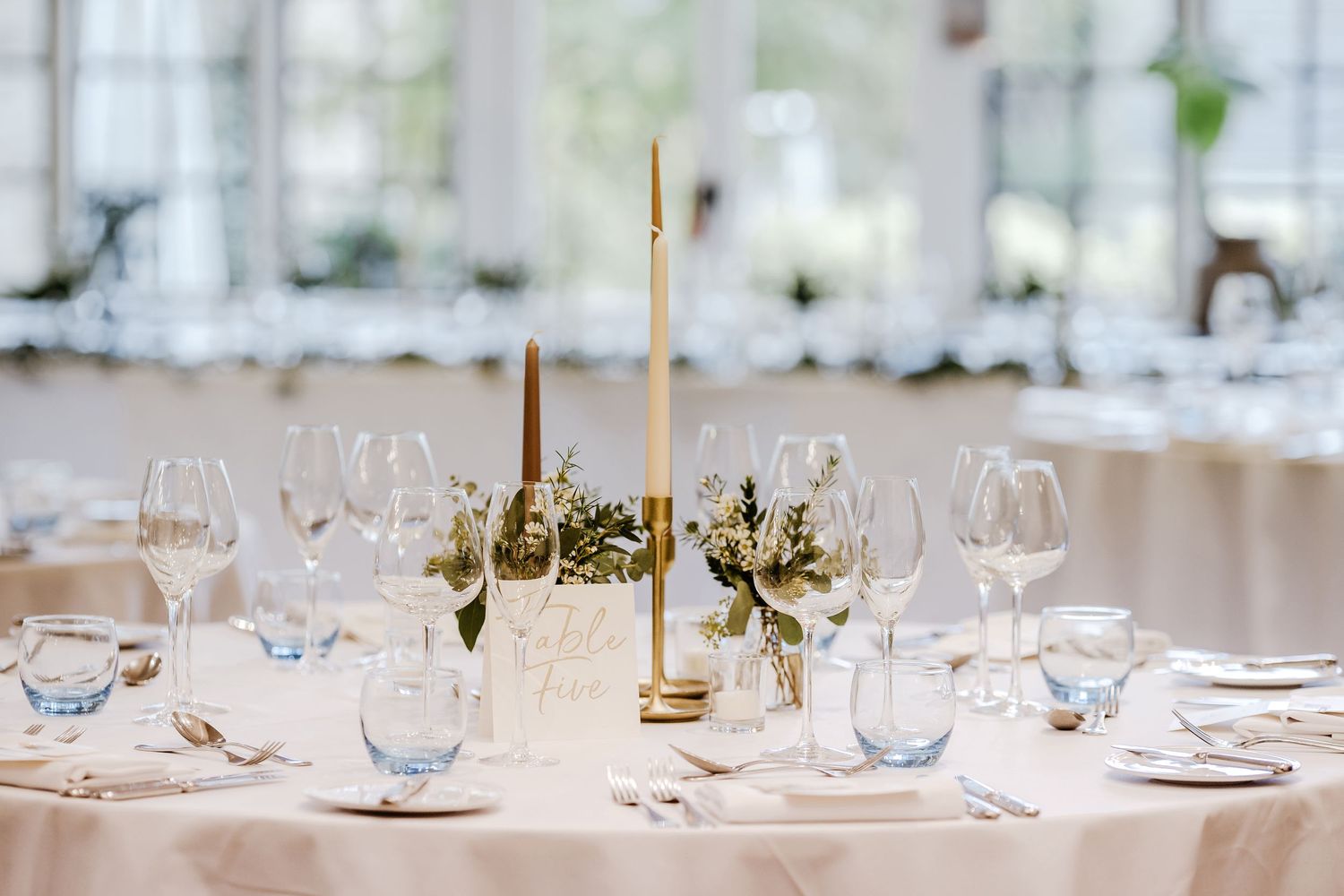 An elegant wedding table setting with tall candles, wine glasses, and delicate floral arrangements.