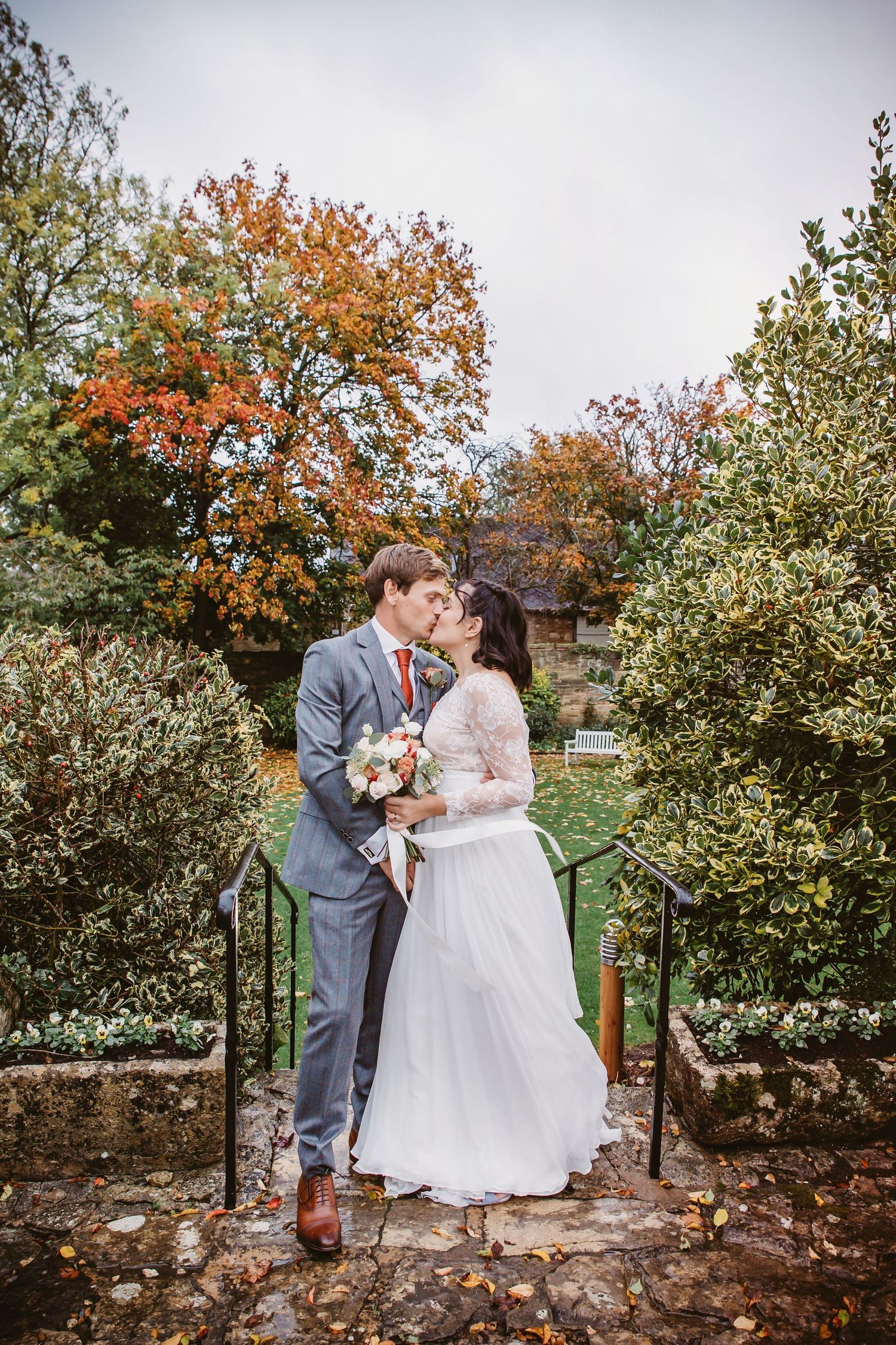 Couple sharing an intimate moment on stone steps surrounded by fall foliage and greenery.