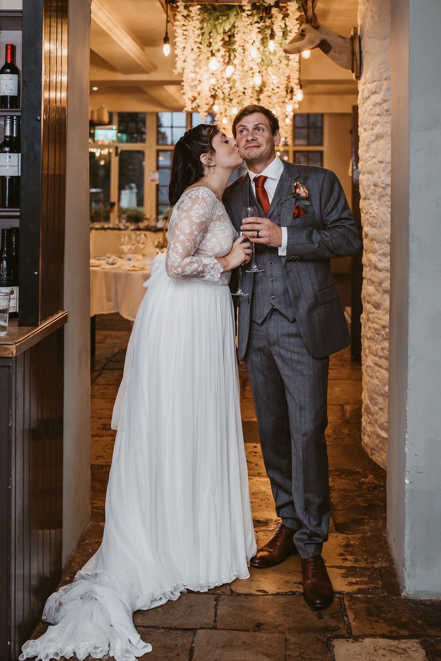 A romantic wedding moment with a couple sharing drinks under an elegant crystal chandelier.