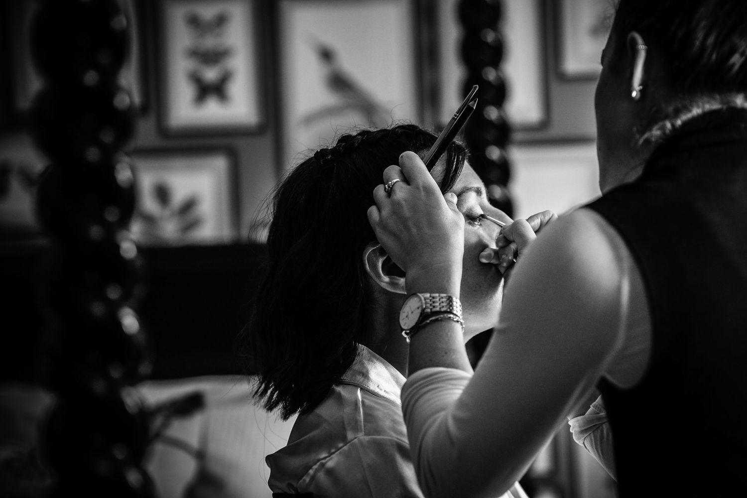 Black and white photo showing preparation moment with makeup application.