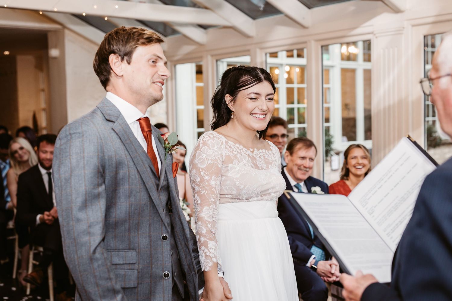 Couple stands at altar during indoor wedding ceremony with exposed beam ceiling.