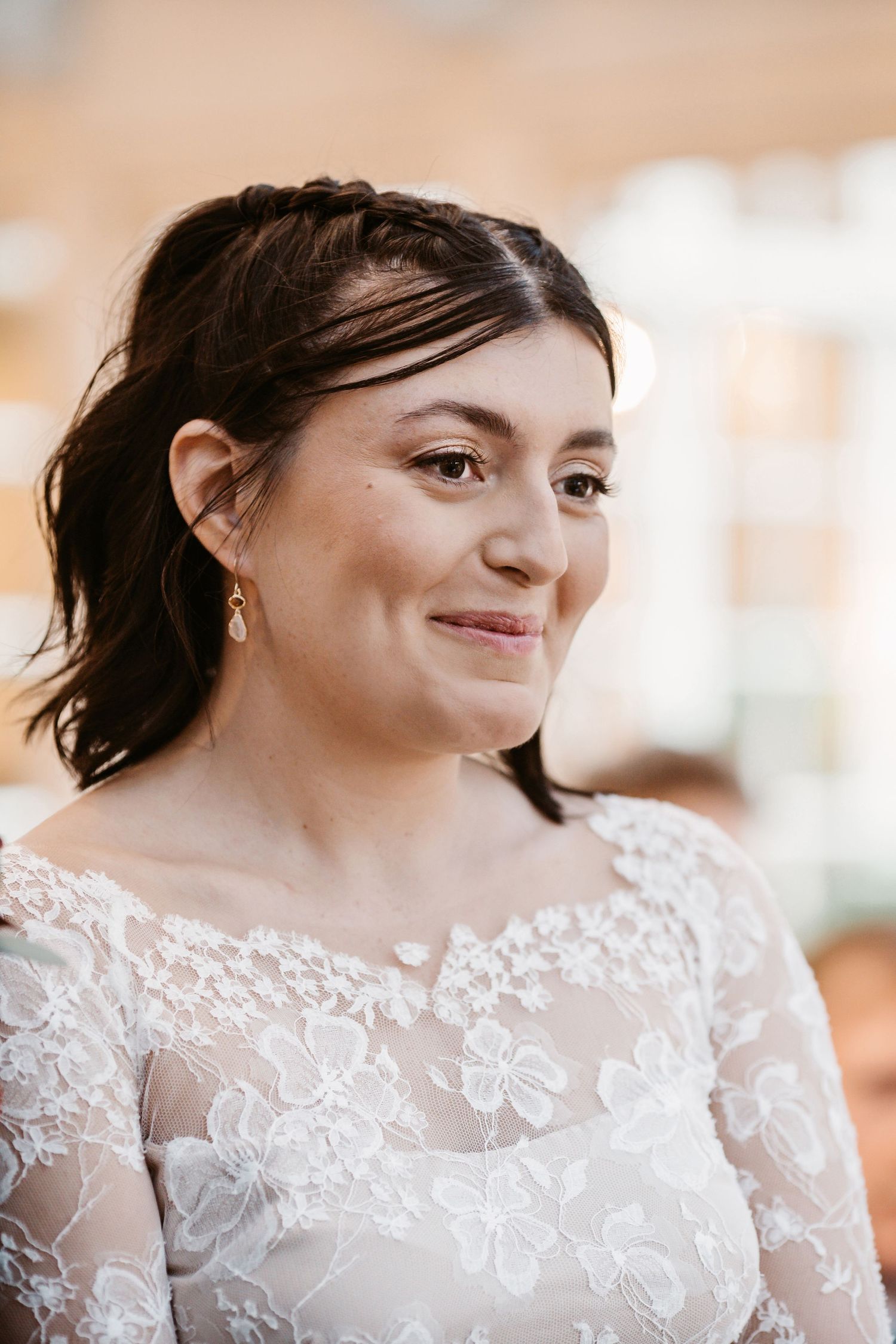 Close up of someone wearing delicate lace wedding dress with natural makeup and dark hair.