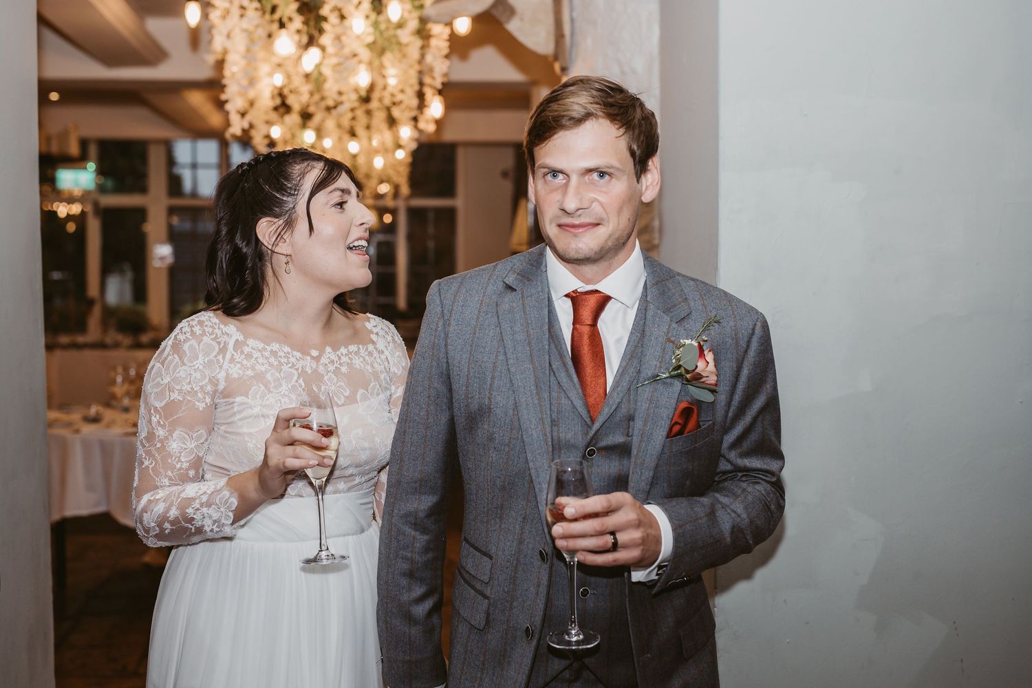 A celebration toast under elegant chandelier lighting at a wedding reception.