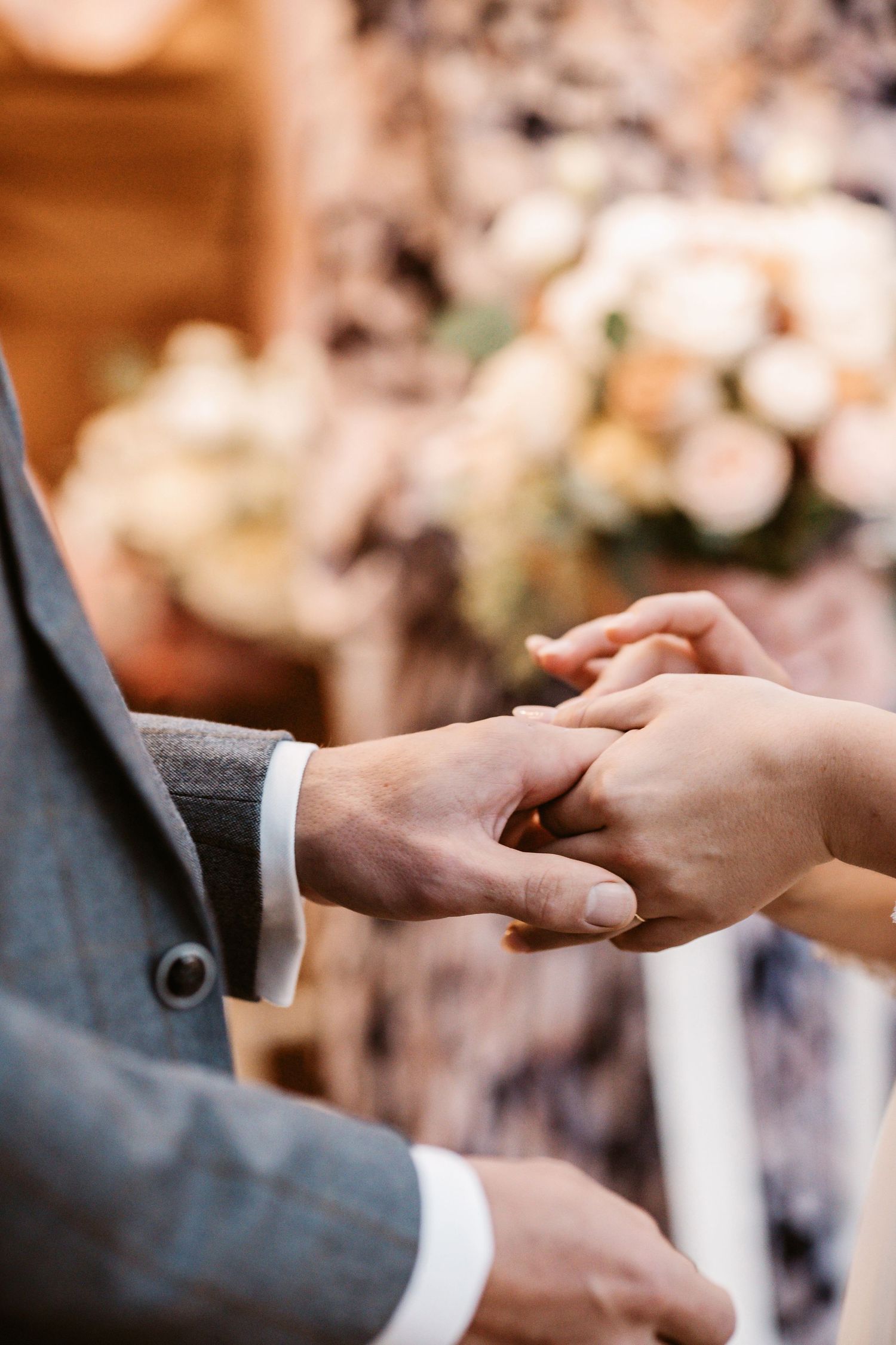 A close-up of hands exchanging wedding rings during a ceremony.