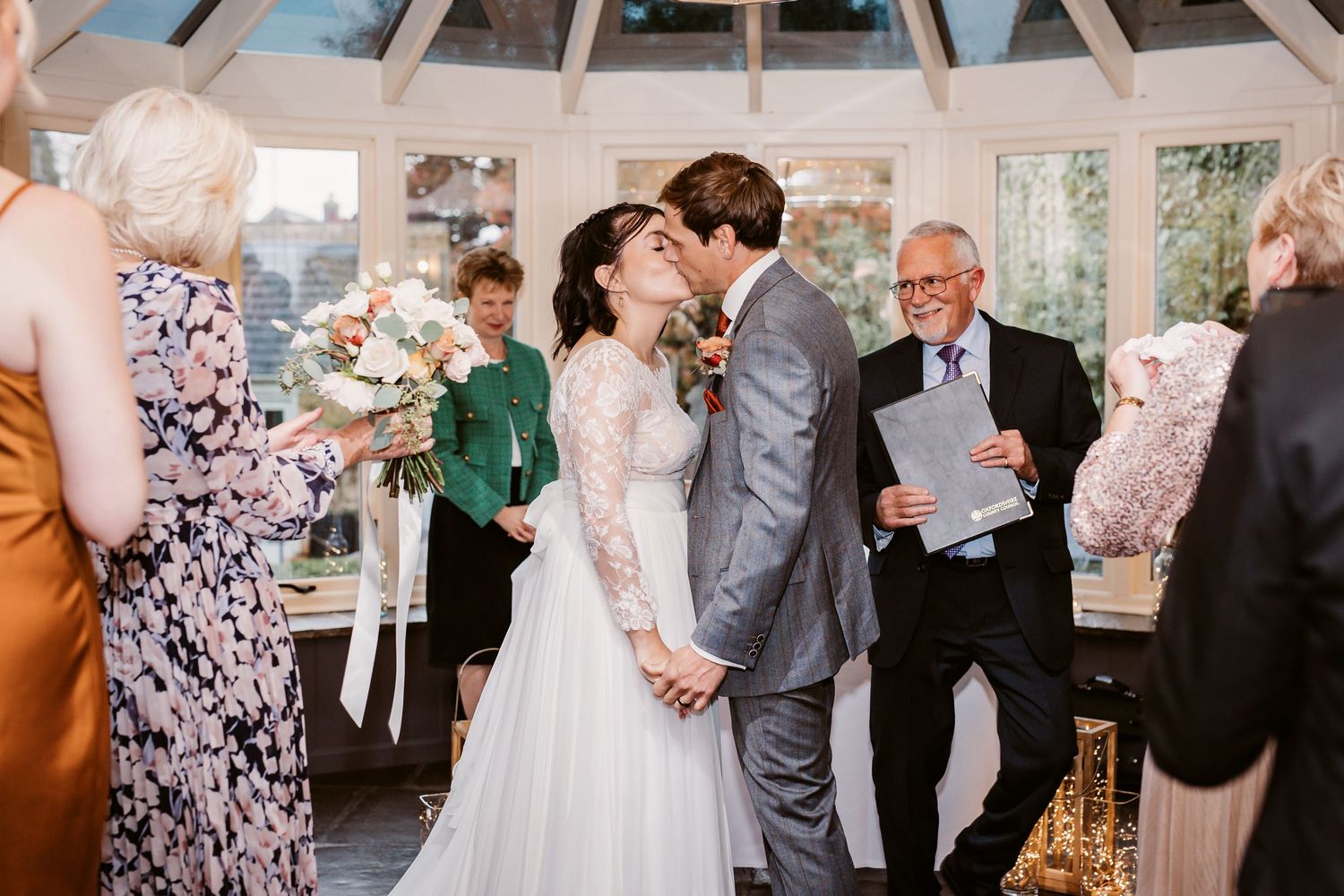 A joyful wedding ceremony taking place in a bright conservatory setting.