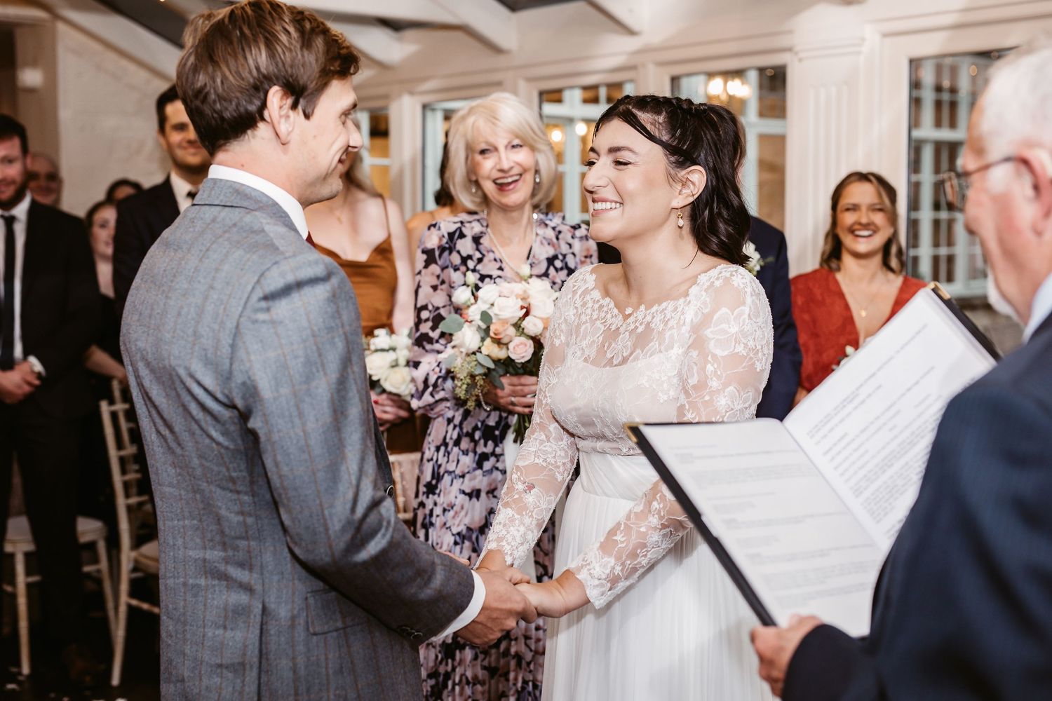 A wedding ceremony in progress with the couple exchanging rings in an indoor venue.