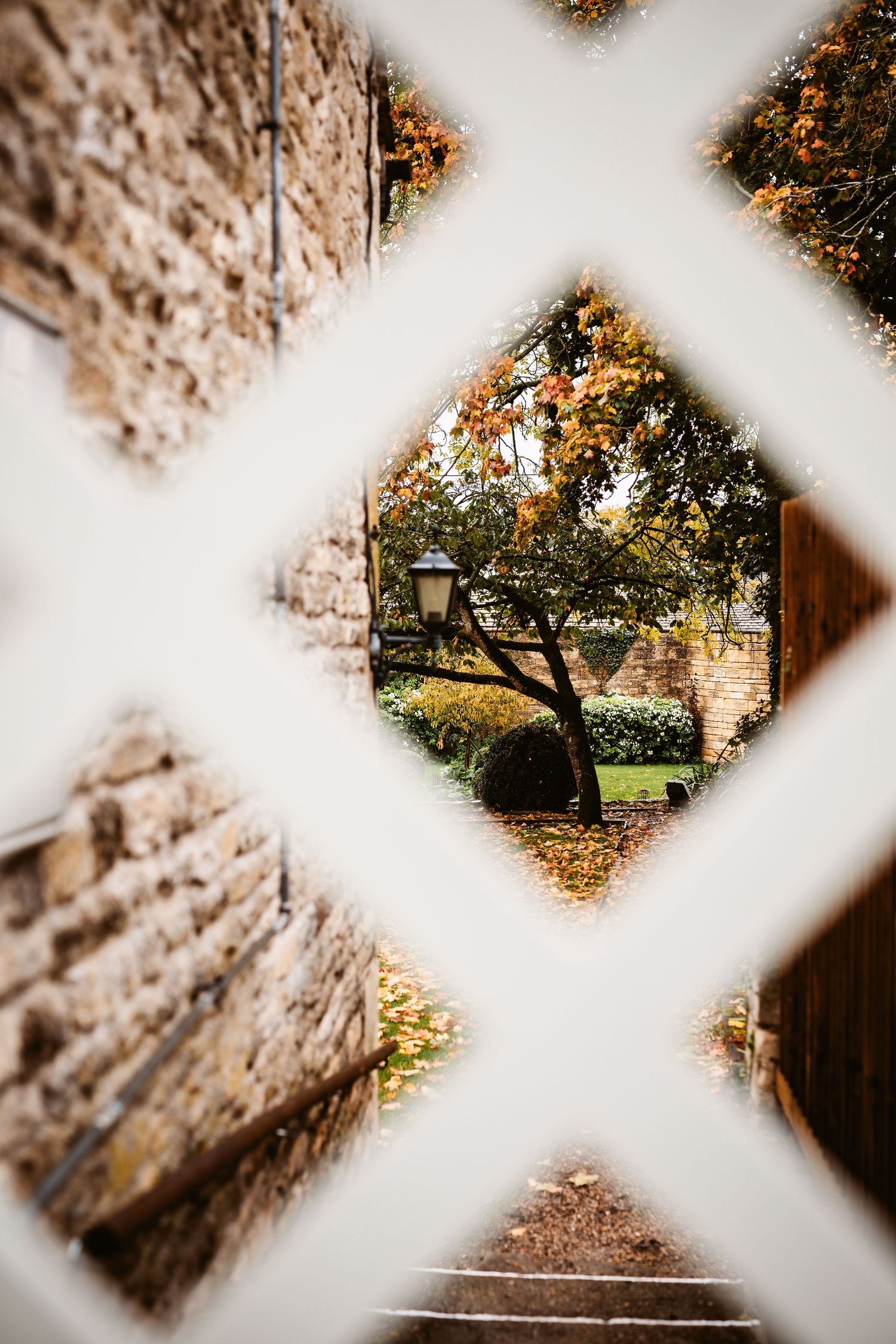 A creative view through a diamond-shaped window frame showing a garden with autumn colors.