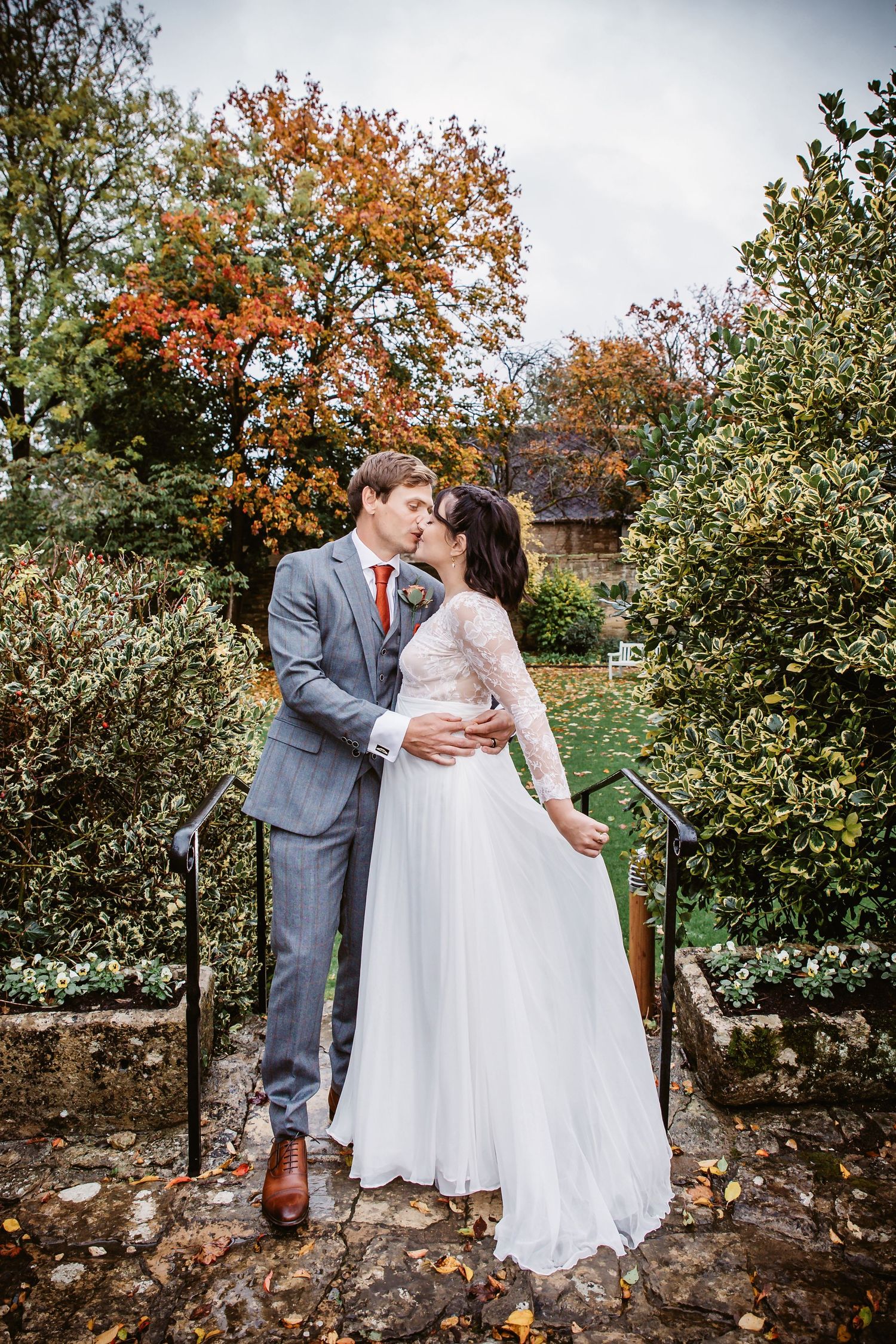 Intimate wedding moment captured with autumn colors and stone garden backdrop.