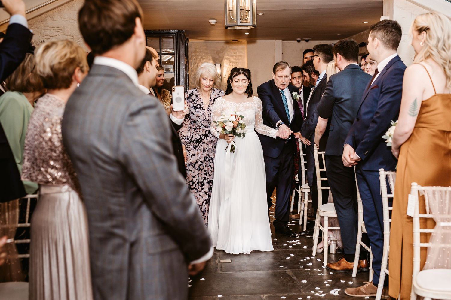 Wedding ceremony guests line the aisle as couple walks through.