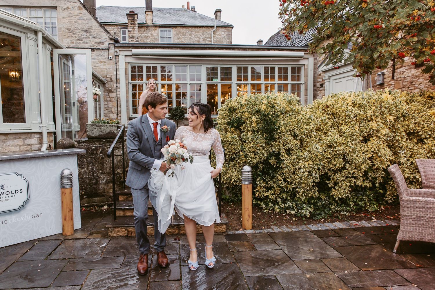 Couple walks arm in arm outside venue with autumn foliage in background.