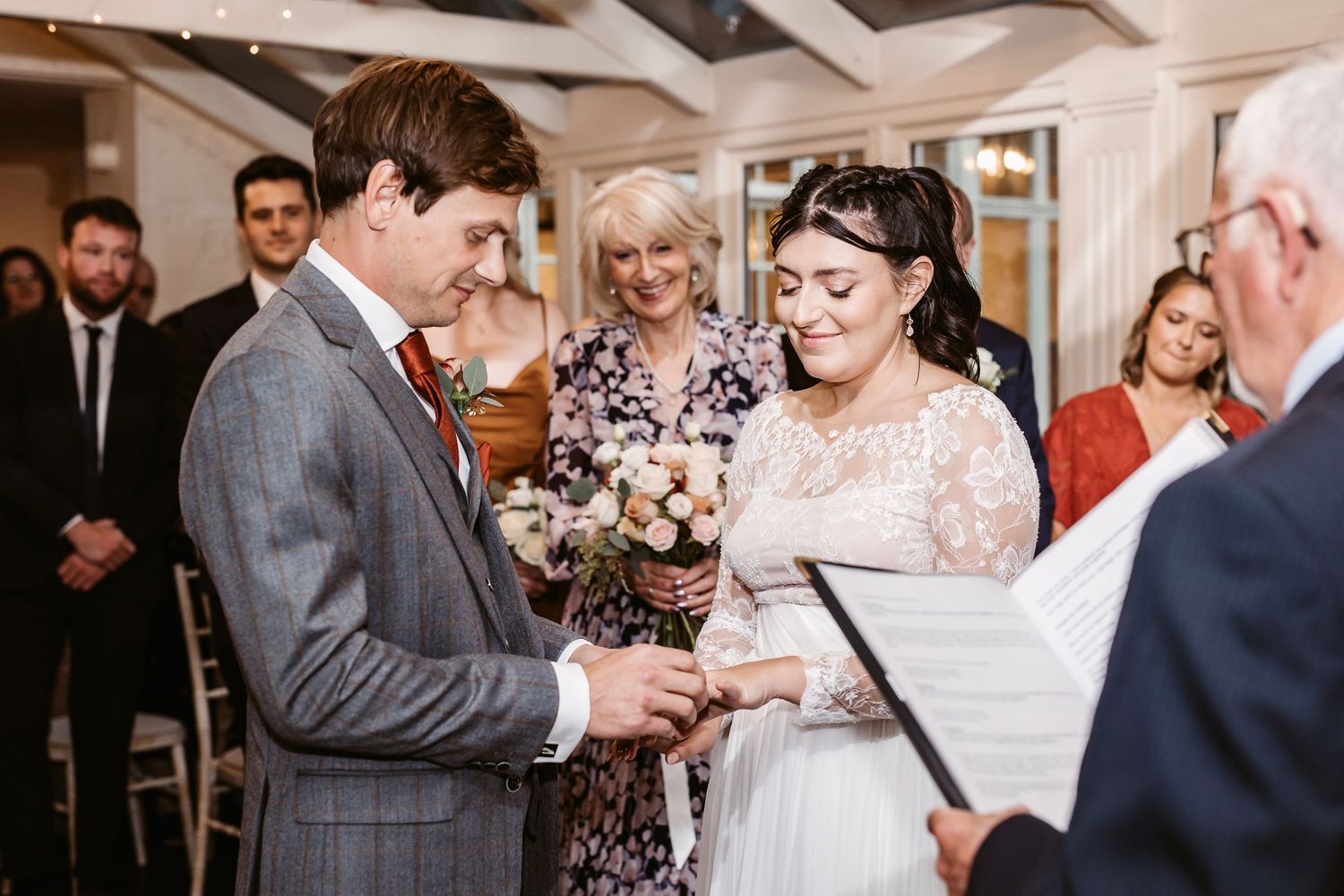 A wedding ceremony being performed with guests watching in an indoor venue.