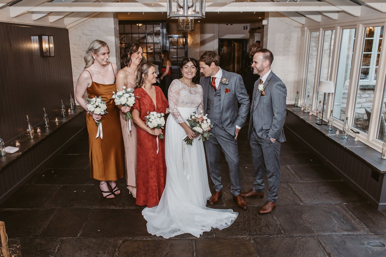 Small wedding party group portrait in venue hallway with mixed formal attire.