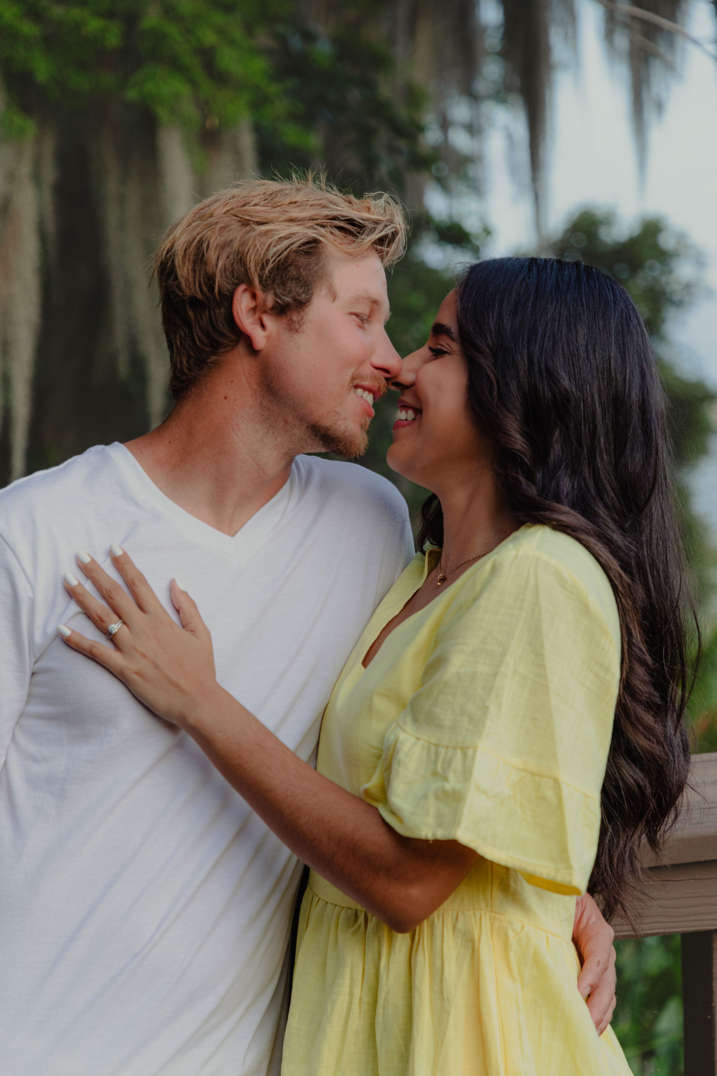 A romantic moment between two people in white and yellow outfits on a wooden deck.