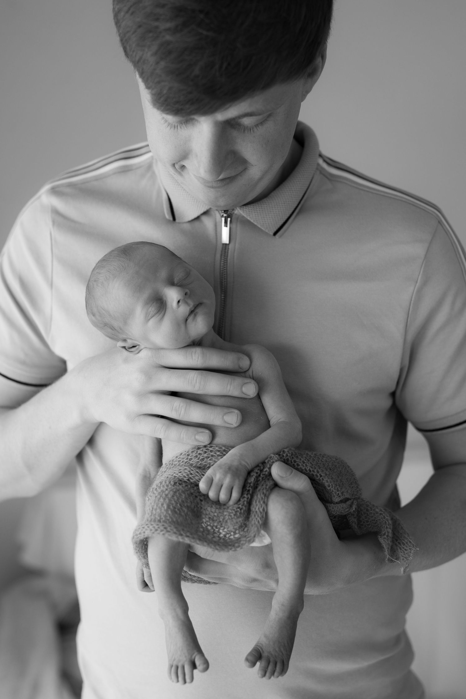 Black and white portrait of parent tenderly holding sleeping newborn baby.