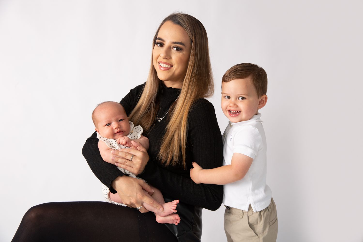Family portrait with mother and two children against white background.