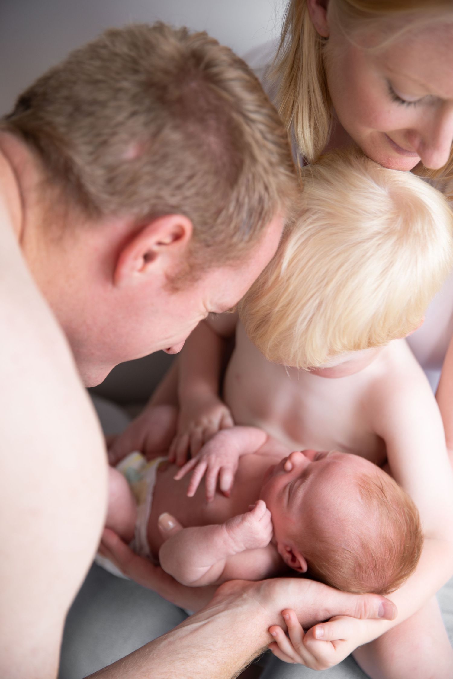 Parents lovingly cradling their newborn baby in a tender family moment.