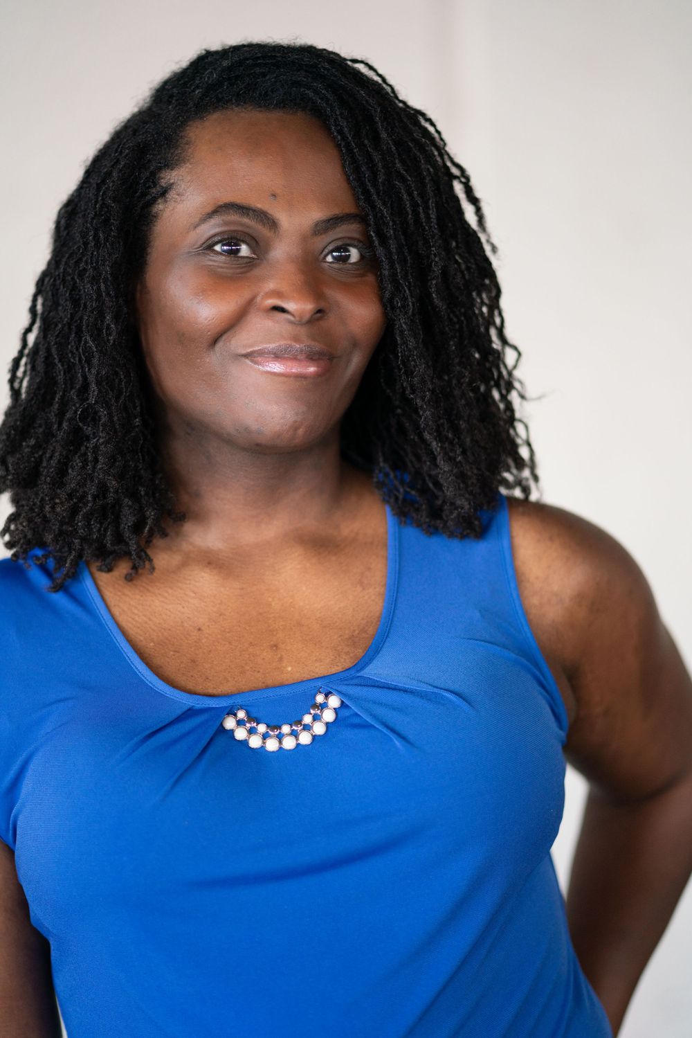 Professional portrait series showing a blue sleeveless top with pearl necklace against white background.