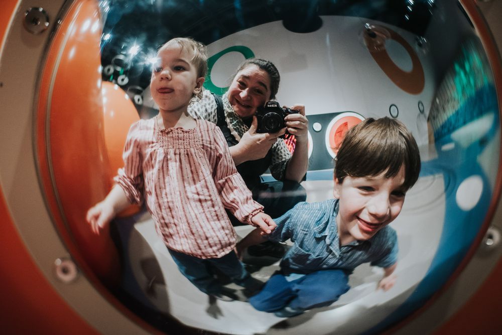 Reflection to 2 little kids and their mom as they look into a sphere at Canadian Museum of Science and Technology.
