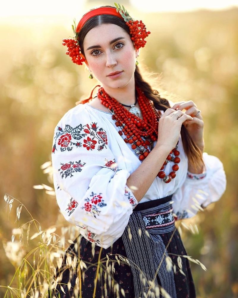 Traditional Ukrainian folk costume with embroidered blouse and red coral accessories.